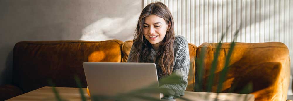 Woman working from home smiling on her laptop